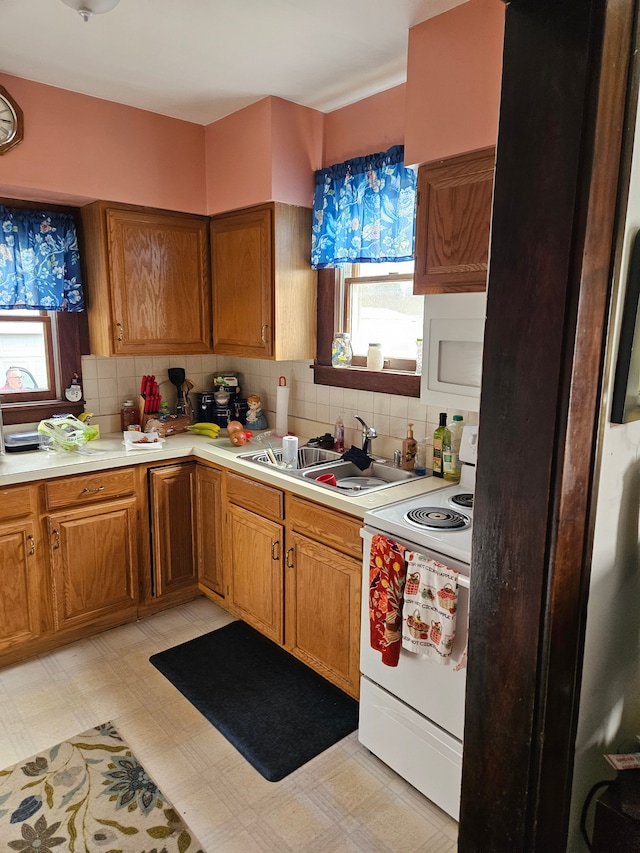 kitchen with backsplash, light floors, light countertops, white appliances, and a sink