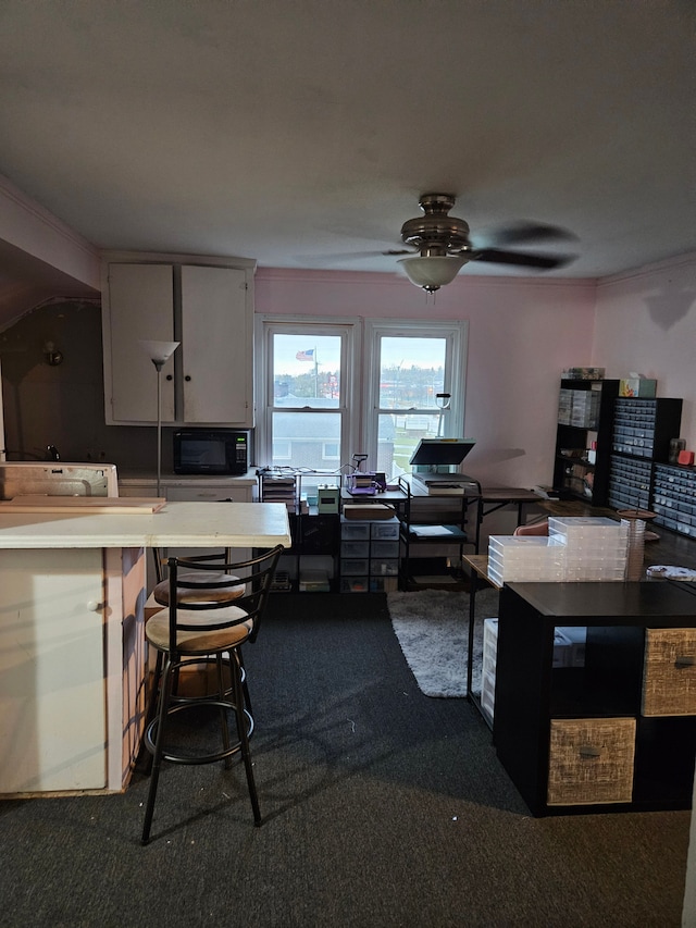 kitchen with light countertops, dark colored carpet, black microwave, and ceiling fan