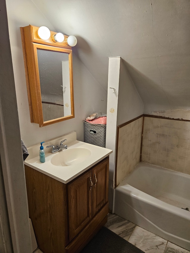 full bath with vanity, lofted ceiling, and a tub