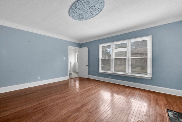 spare room featuring a textured ceiling, baseboards, and hardwood / wood-style flooring