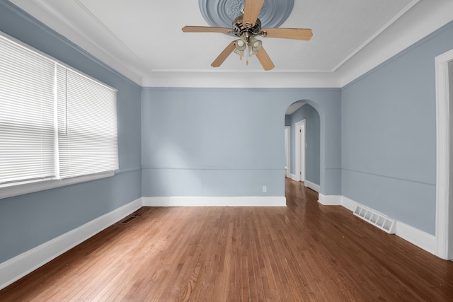 unfurnished room featuring visible vents, ceiling fan, baseboards, wood finished floors, and arched walkways