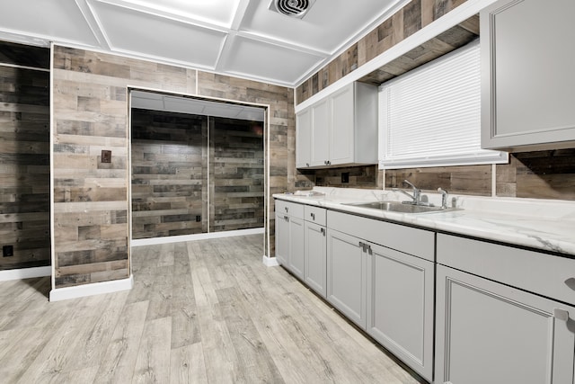 kitchen with visible vents, wood walls, light wood-style flooring, and a sink