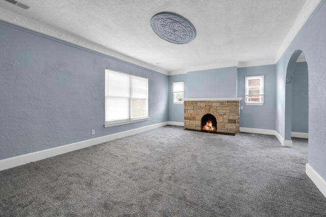 unfurnished living room featuring carpet flooring, a healthy amount of sunlight, a fireplace, and a textured wall