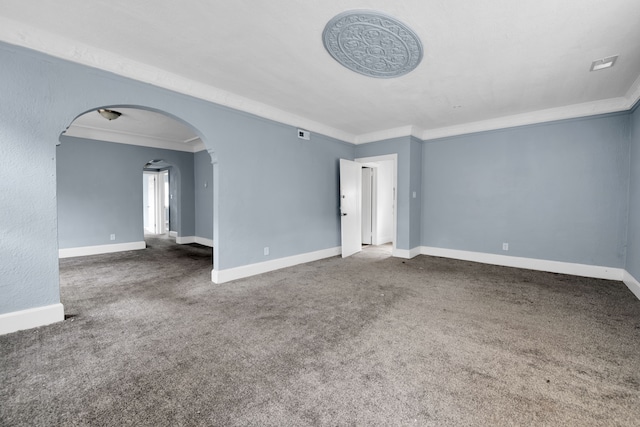 carpeted spare room featuring crown molding, baseboards, and arched walkways