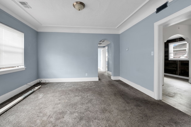 spare room featuring visible vents, baseboards, arched walkways, and carpet floors