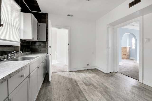 kitchen with a sink, visible vents, arched walkways, and light countertops