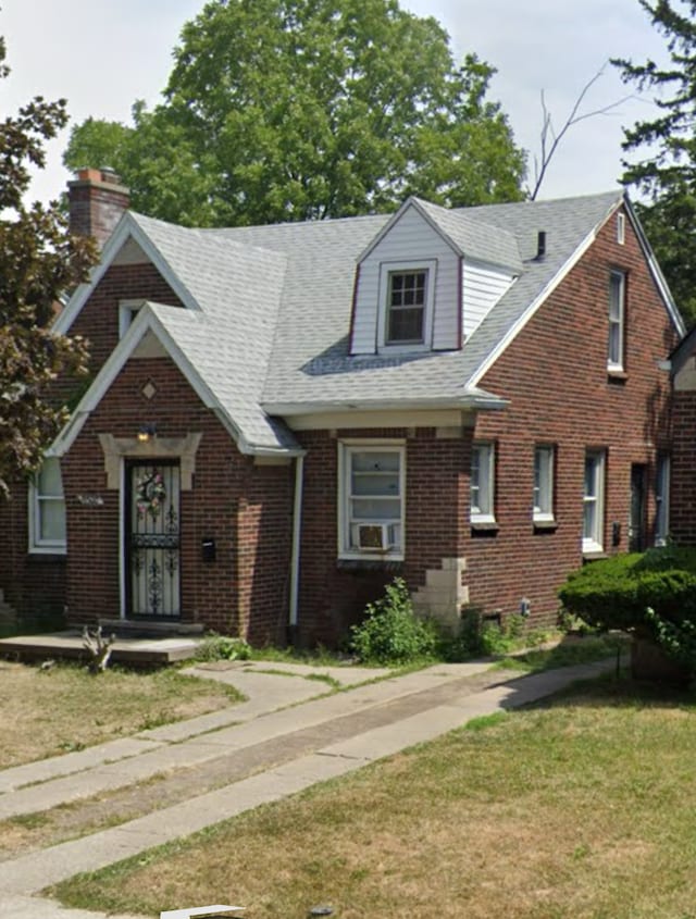 view of front of home with brick siding, a front lawn, and roof with shingles