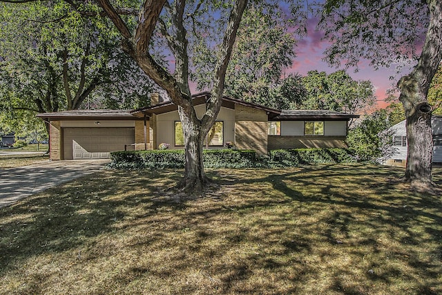 mid-century home with brick siding, concrete driveway, a garage, and a front yard