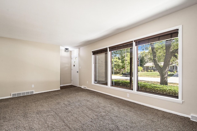 spare room with visible vents, dark carpet, and baseboards