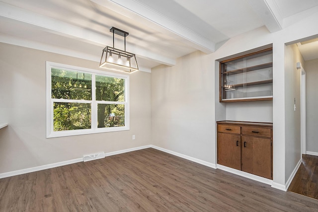 unfurnished dining area with beamed ceiling, baseboards, visible vents, and dark wood finished floors