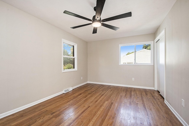 empty room featuring a wealth of natural light, baseboards, and wood finished floors