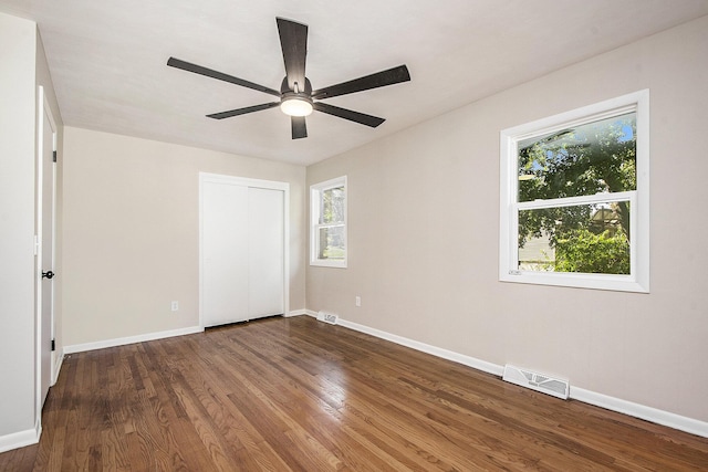 unfurnished bedroom featuring visible vents, baseboards, a closet, and wood finished floors