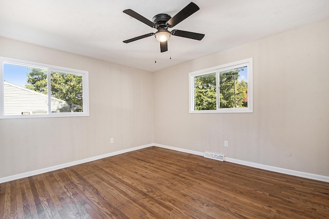 empty room with ceiling fan, wood finished floors, visible vents, and baseboards