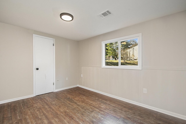 spare room with wood finished floors, visible vents, and baseboards