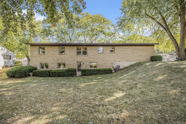 rear view of house featuring brick siding and a yard