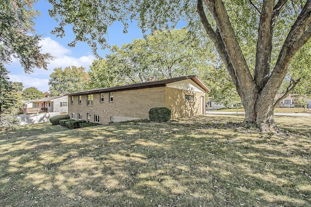 view of side of property featuring a yard, brick siding, and fence