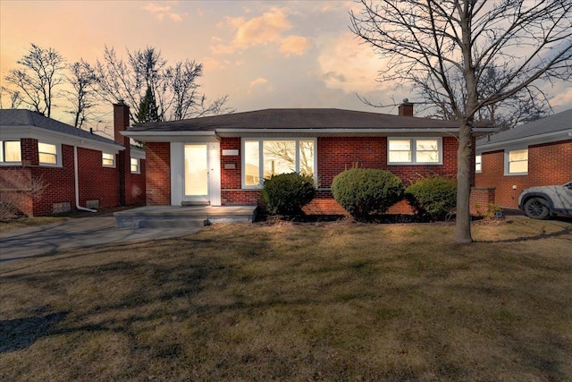 single story home with brick siding, a chimney, and a front yard