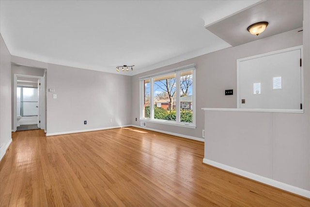 unfurnished living room with visible vents, light wood-style floors, and baseboards