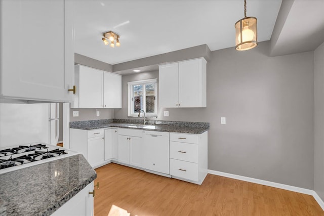 kitchen with light wood finished floors, baseboards, white dishwasher, white cabinets, and a sink