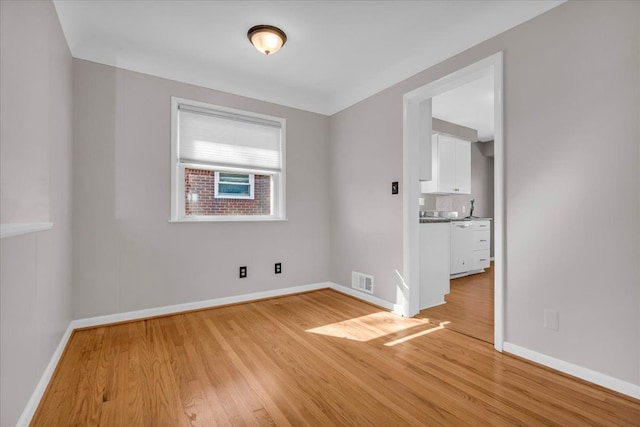 spare room featuring baseboards, visible vents, and light wood-type flooring