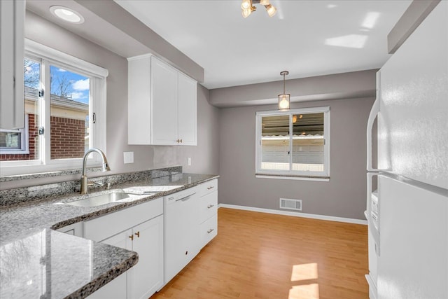 kitchen with white cabinets, visible vents, freestanding refrigerator, and a sink