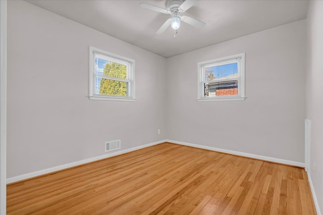 empty room with visible vents, ceiling fan, light wood-type flooring, and baseboards