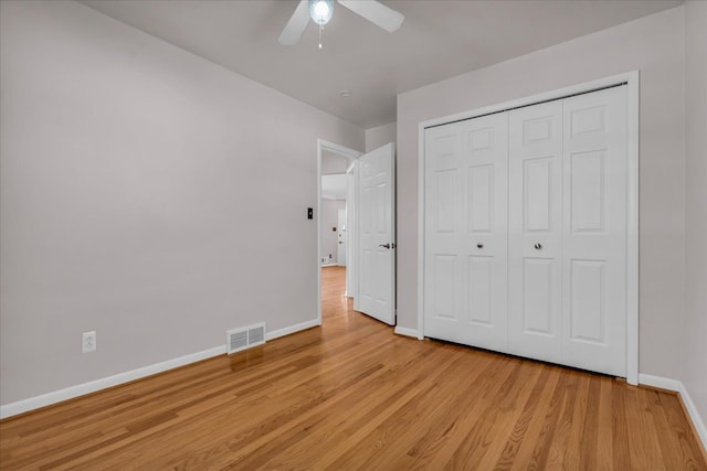 unfurnished bedroom featuring light wood-type flooring, visible vents, a closet, baseboards, and ceiling fan