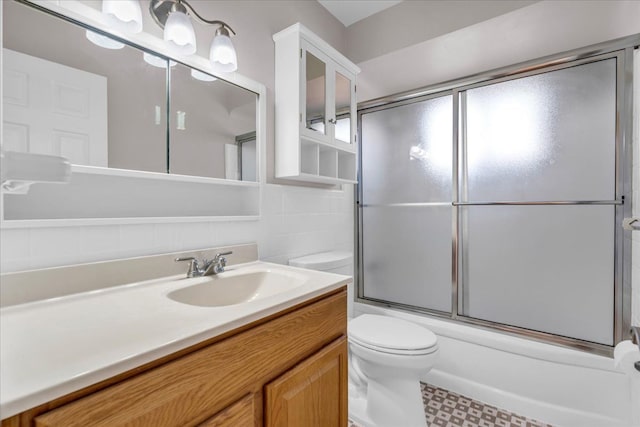 full bathroom with bath / shower combo with glass door, toilet, and vanity