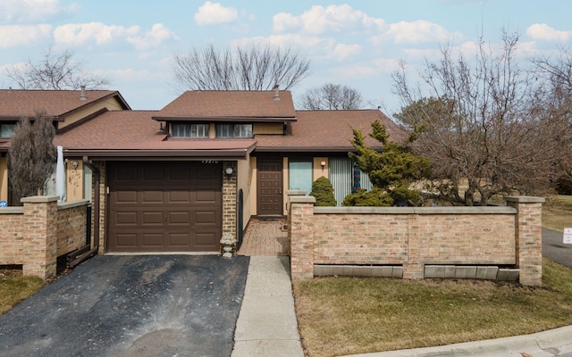 view of front of house featuring a fenced front yard, a garage, driveway, and a shingled roof