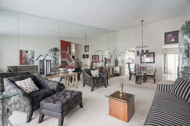 living area featuring wallpapered walls, a textured ceiling, stairs, and carpet floors