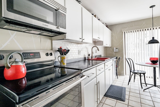 kitchen with light tile patterned floors, a sink, white cabinets, appliances with stainless steel finishes, and tasteful backsplash