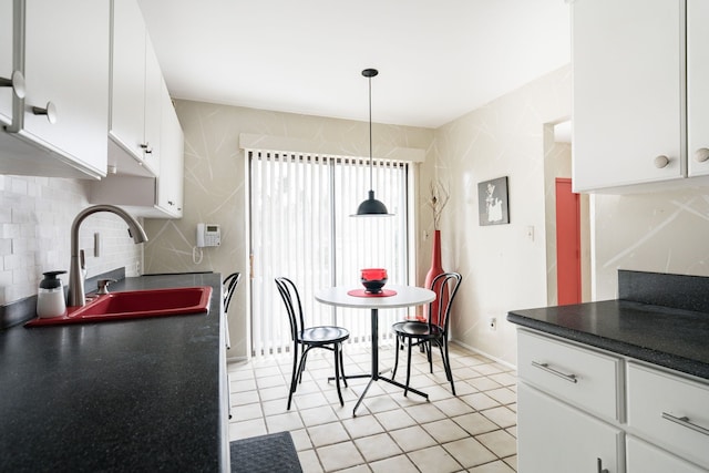 kitchen with light tile patterned flooring, a sink, white cabinetry, dark countertops, and backsplash