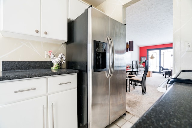 kitchen featuring stainless steel refrigerator with ice dispenser, a textured ceiling, white cabinetry, light tile patterned floors, and light colored carpet