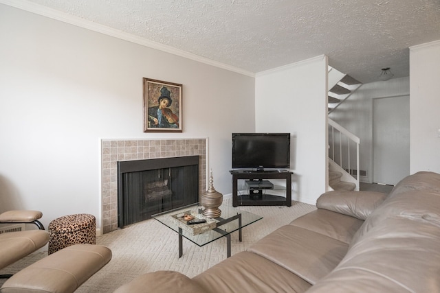 carpeted living area featuring a tiled fireplace, a textured ceiling, stairs, and ornamental molding