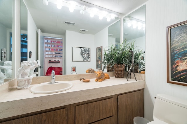 bathroom with vanity, toilet, and visible vents