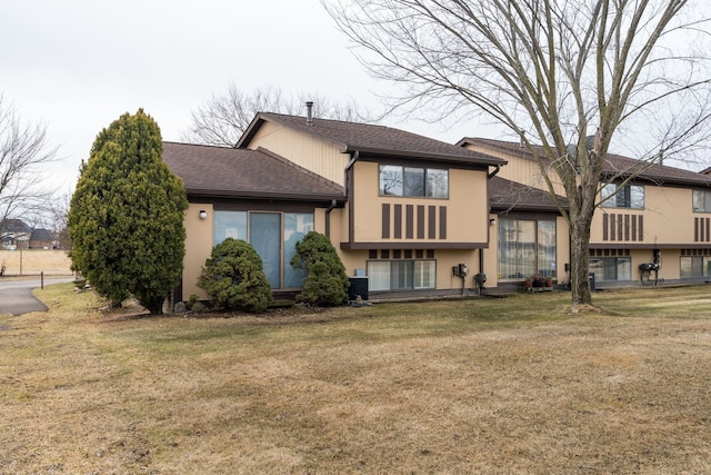 back of property featuring central air condition unit, a lawn, and roof with shingles