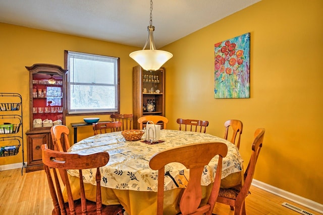 dining space featuring visible vents, light wood-style flooring, and baseboards