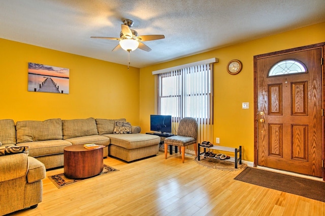 living area with plenty of natural light, a textured ceiling, wood finished floors, and a ceiling fan