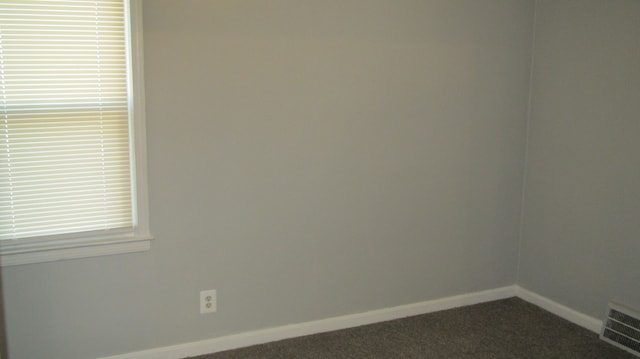 unfurnished room featuring baseboards, visible vents, and dark colored carpet