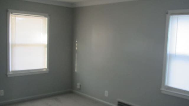 empty room with plenty of natural light, a baseboard heating unit, and baseboards