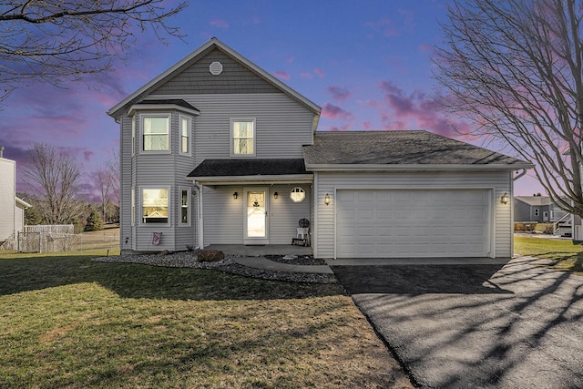 traditional-style home featuring a yard, a garage, driveway, and fence