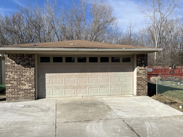 garage featuring concrete driveway and fence