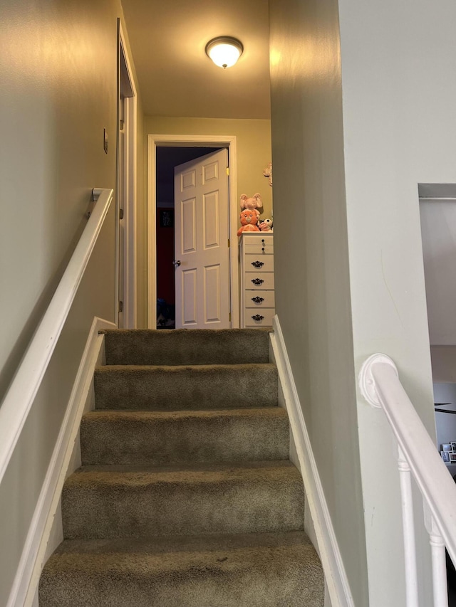 stairway with baseboards and carpet flooring