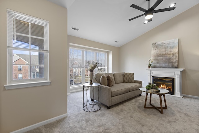 living room with visible vents, a glass covered fireplace, carpet, baseboards, and vaulted ceiling