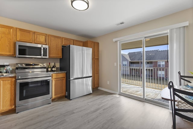 kitchen featuring light wood-type flooring, stainless steel appliances, visible vents, and brown cabinetry