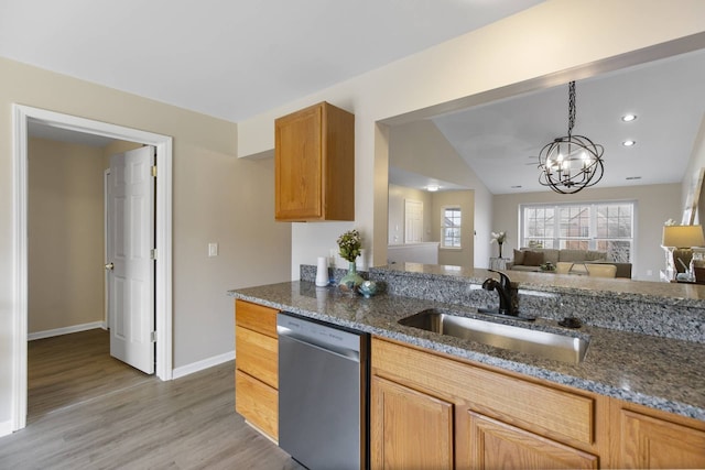 kitchen with dark stone counters, light wood-style flooring, a sink, dishwasher, and a chandelier