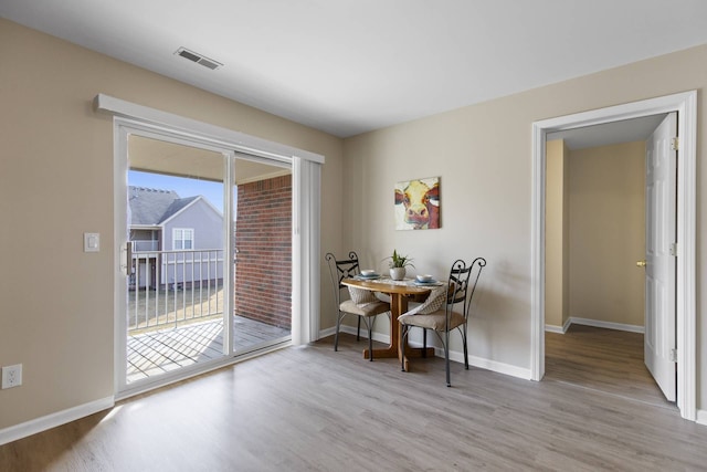 dining area with wood finished floors, visible vents, and baseboards