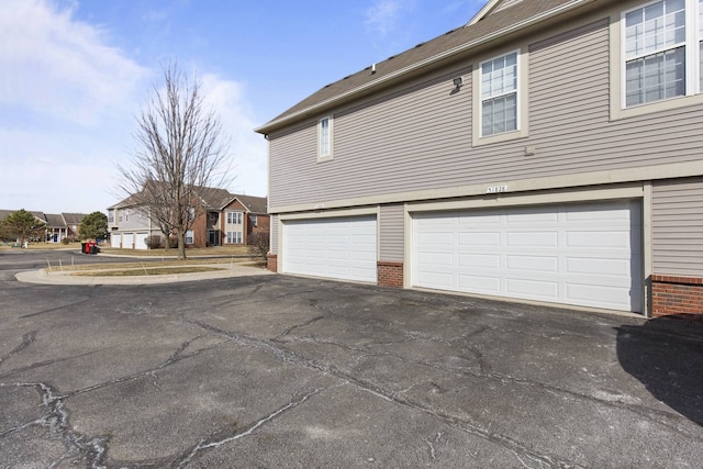 view of home's exterior with aphalt driveway, brick siding, and an attached garage