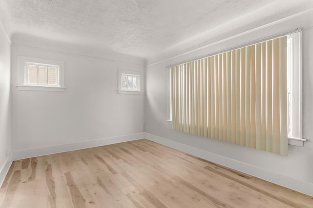 unfurnished room featuring wood finished floors, baseboards, and a textured ceiling