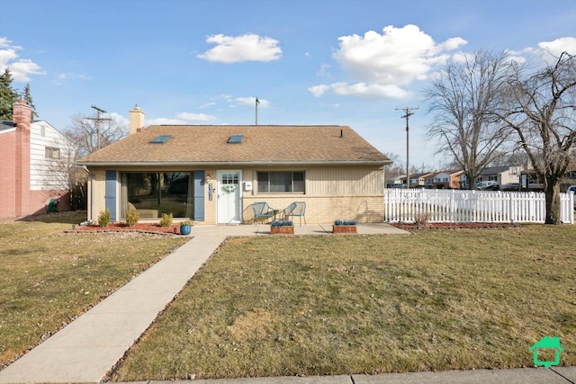 rear view of property with brick siding, a chimney, a yard, and fence